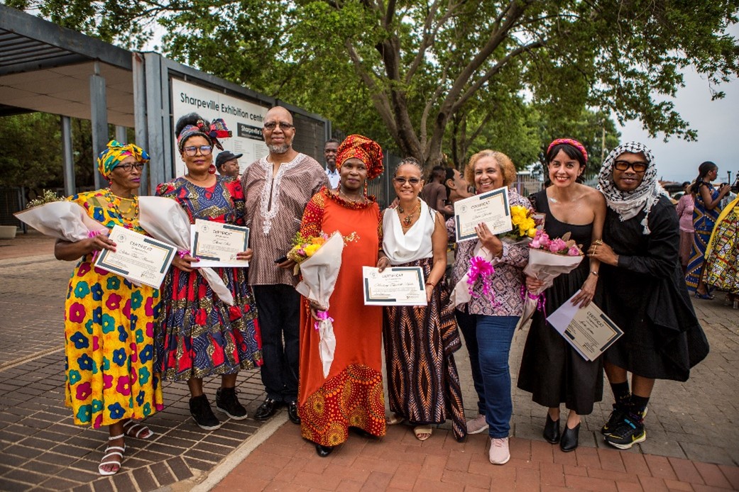 La Embajadora María del Rosario Mina Rojas, el señor Concejal Busang Joshua Tsotetsi, y la diseñadora colombiana Laura Laurens, aparecen junto a lxs cinco costurerxs que culminaron exitosamente el taller: Elizabeth, Tembi, Oma, Fortunate y Pinkie. También aparece Thami Kotlolo, Director de la Fundación Thami Dish.  Foto: Salym Fayad para Embajada de Colombia en Sudáfrica.